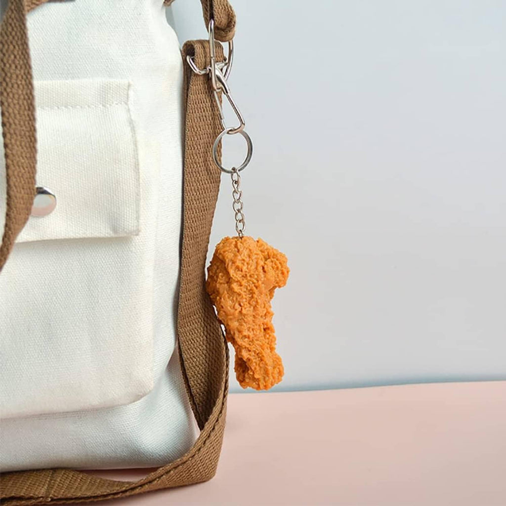 Orange-brown faux fried chicken drumstick keychain with metal hook and ring.