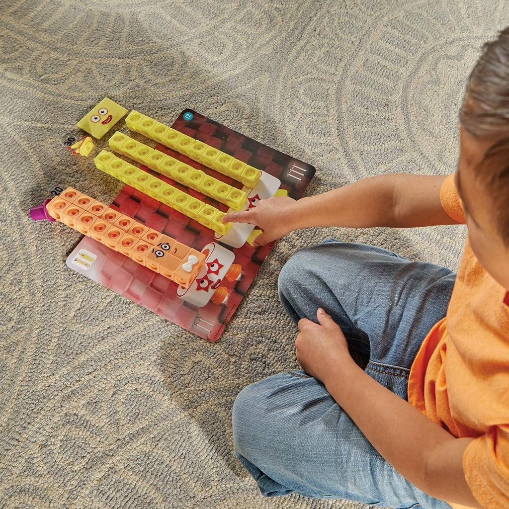 Child arranging large multicolor cube tiles on carpet for Numberblocks math