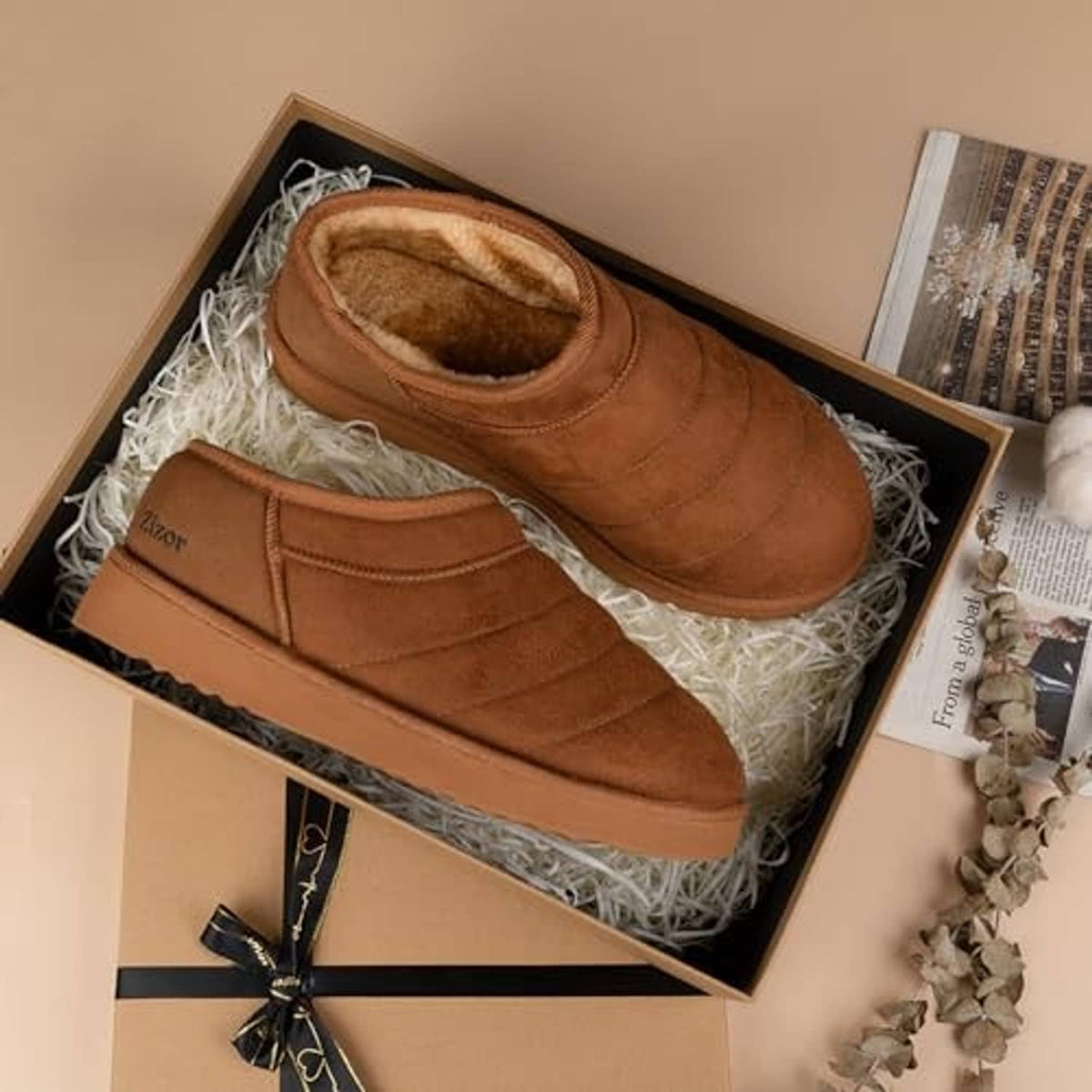 Tan fur-lined suede house shoe slippers in a gift box with white stuffing.