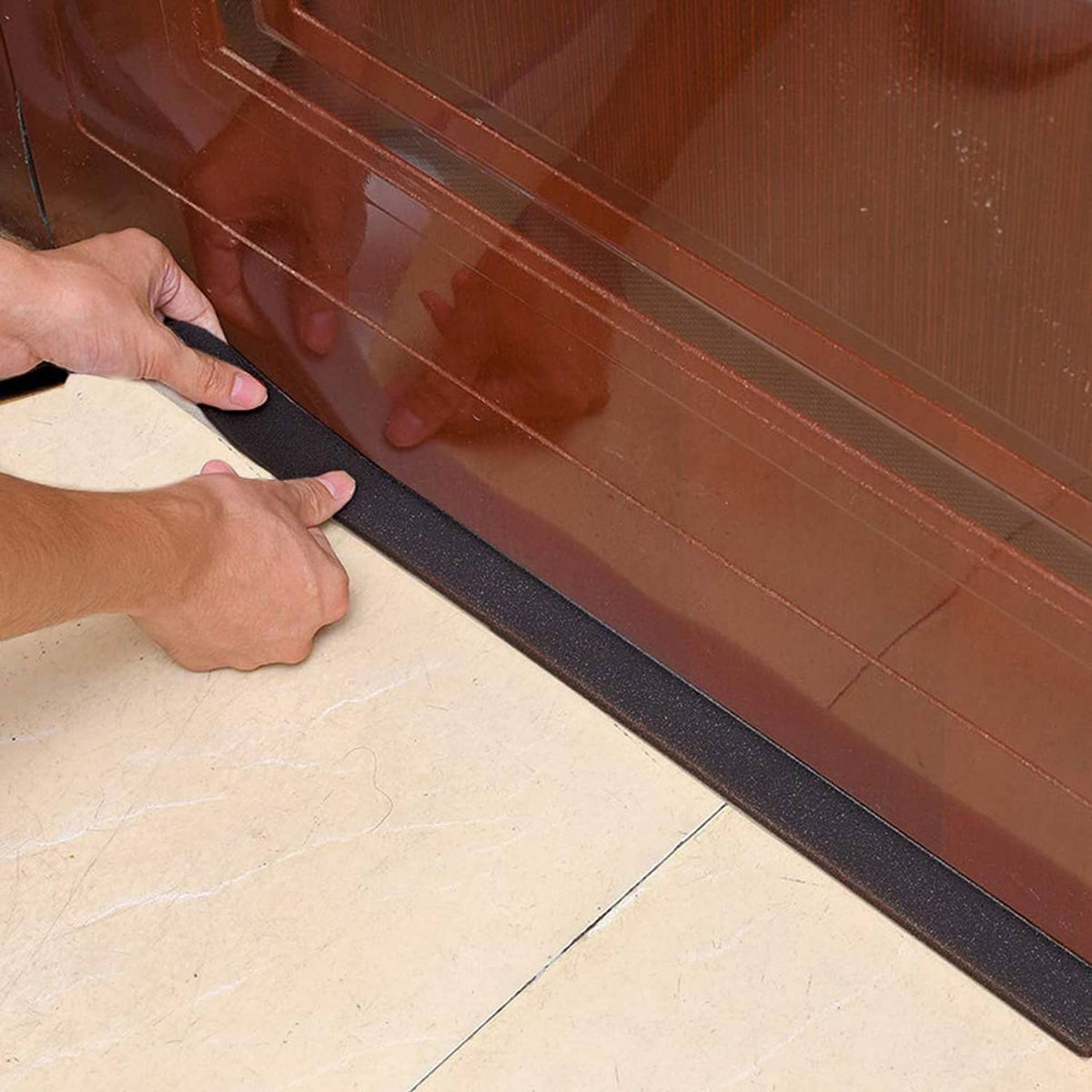 Black neoprene foam strip pressed along a baseboard and floor edge