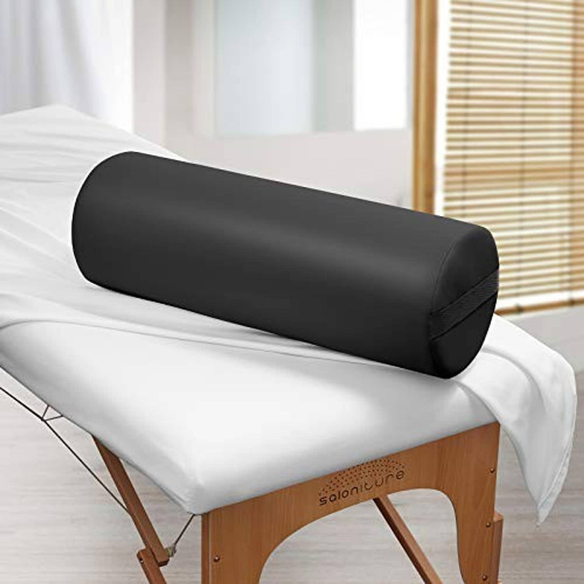 Black cylindrical massage table bolster pillow pad on a treatment table