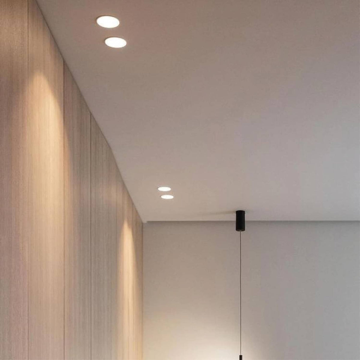 Recessed ceiling spotlights with white housings in a modern wood-and-plaster room