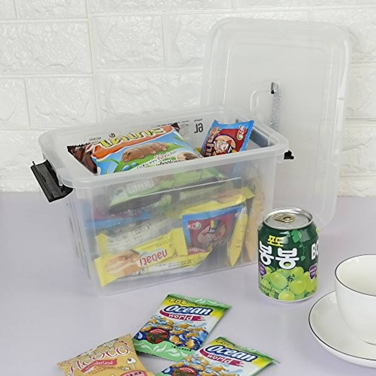 Clear 6-quart storage box with black latches, lid open with snack items inside