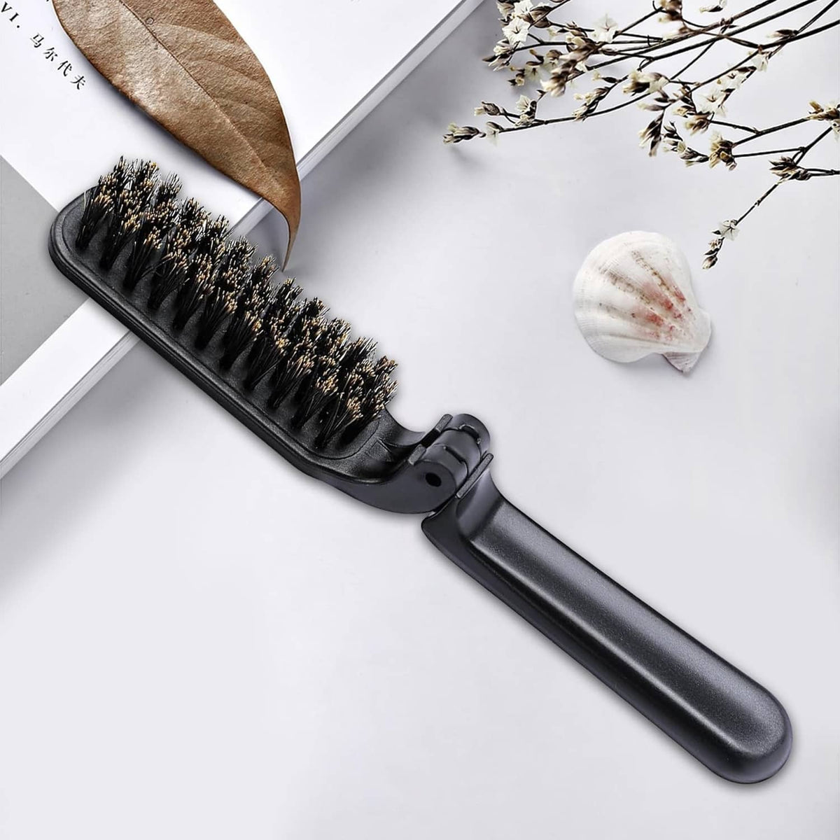 Black mini folding boar bristle hair brush with curved handle and dense bristles