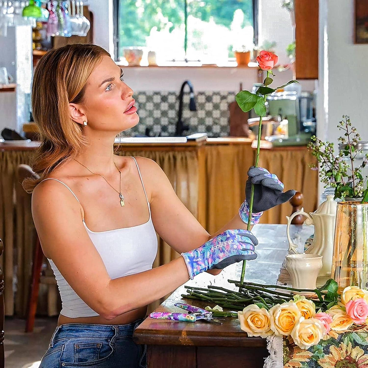 Woman in black and multicolor gardening gloves tending flowers on a kitchen table