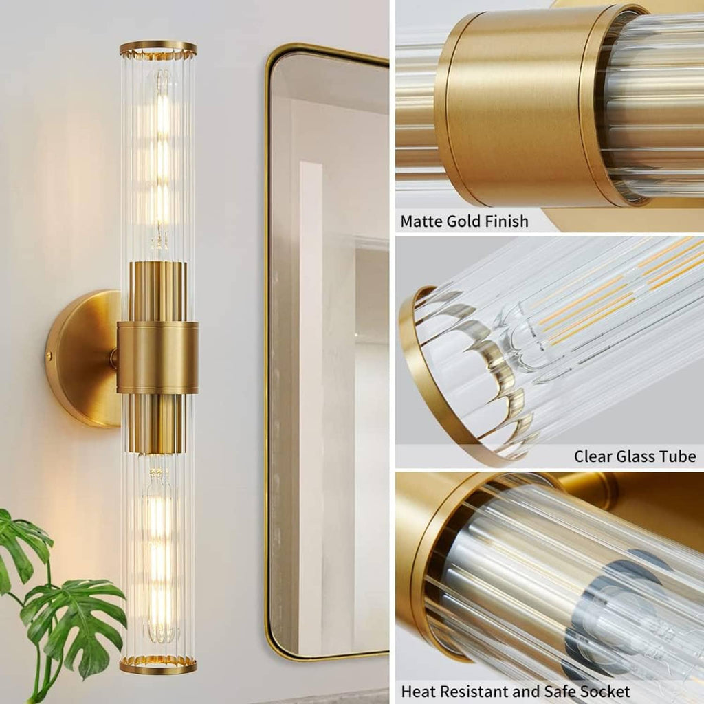 Matte gold vanity wall light with clear glass tube and round wall mount bracket.