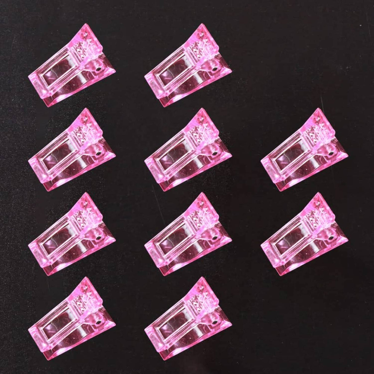 Pink crystal nail tips clips, 10-piece set arranged on a flat surface