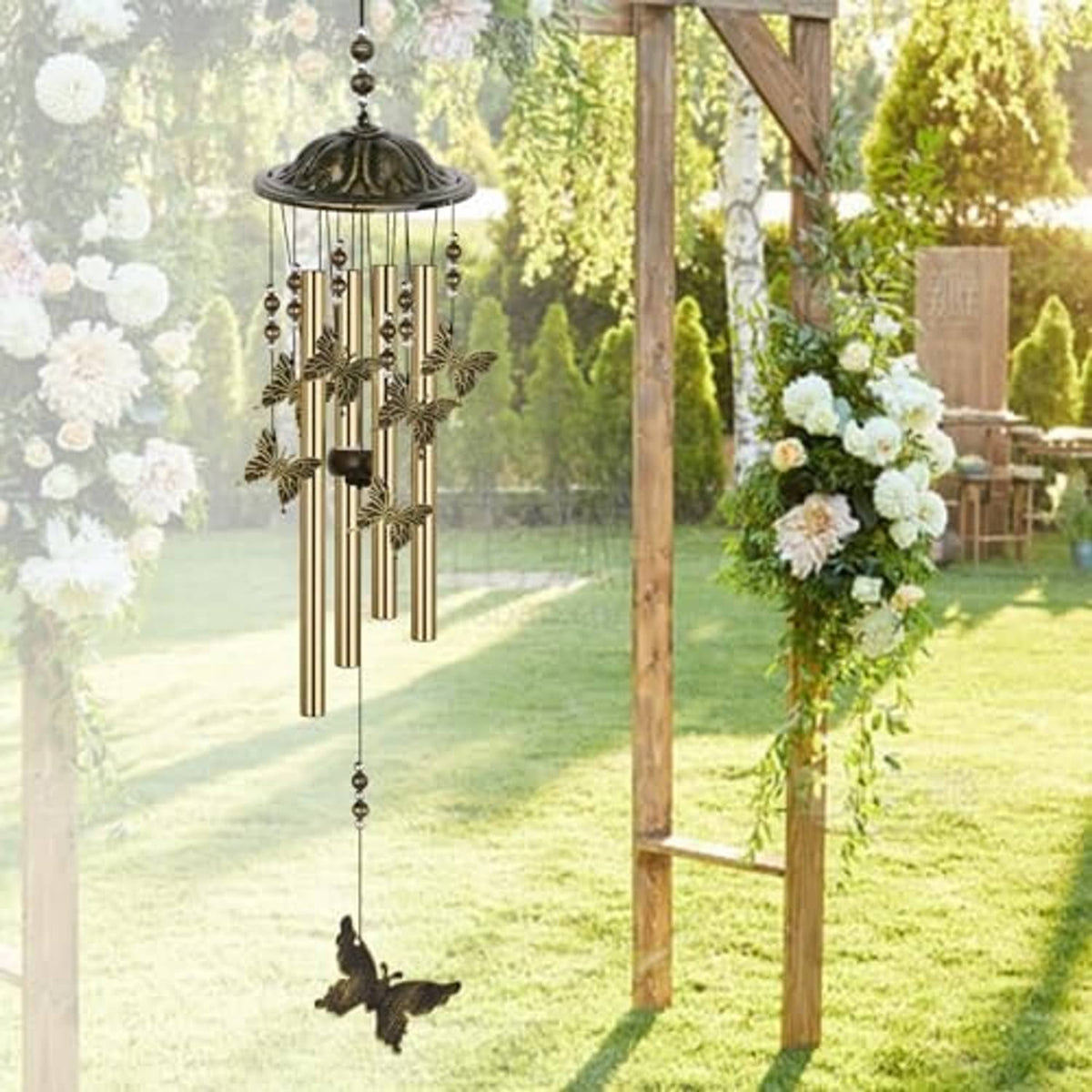 Bronze butterfly wind chime with domed top, hanging rods, and butterfly charm in garden