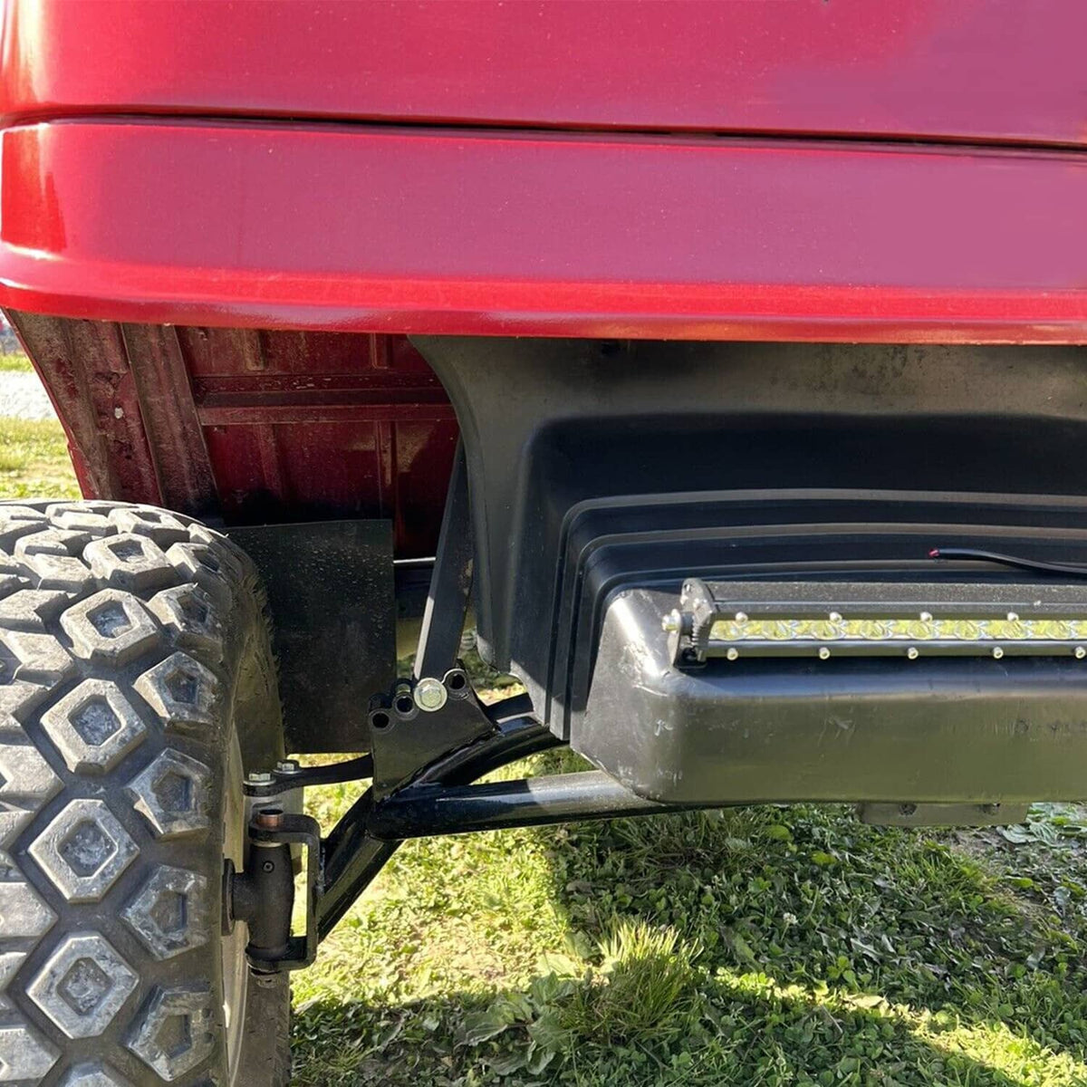 A-arm lift kit installed near the front wheel with black bracket and arm