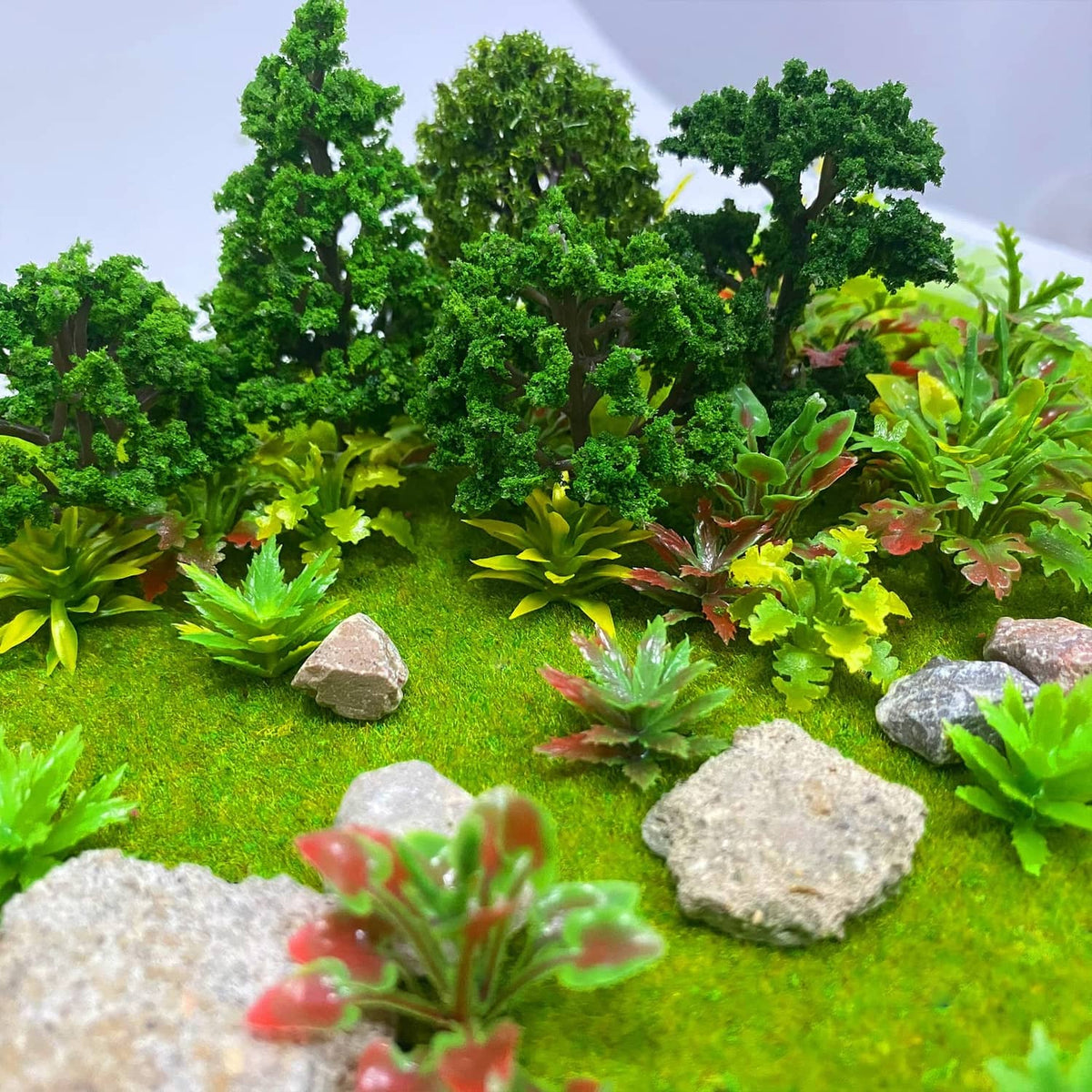 Miniature green model trees and varied succulents on grassy base
