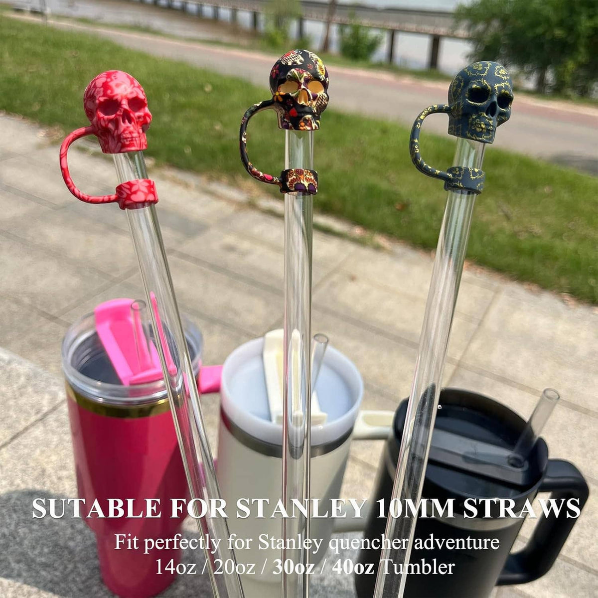 Three 3D silicone skull straw cover caps on clear straws, outdoors