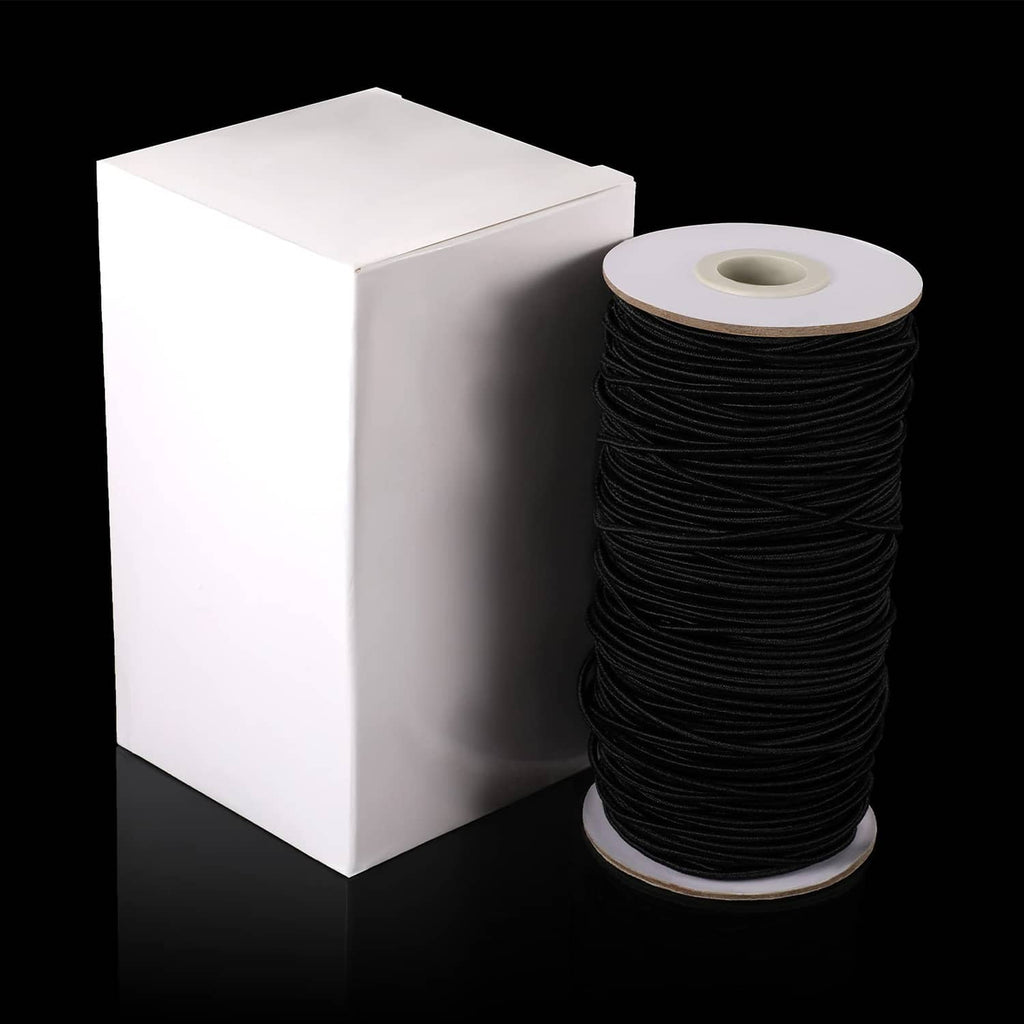 Black elastic cord on spool beside box, thin stretch string for crafts
