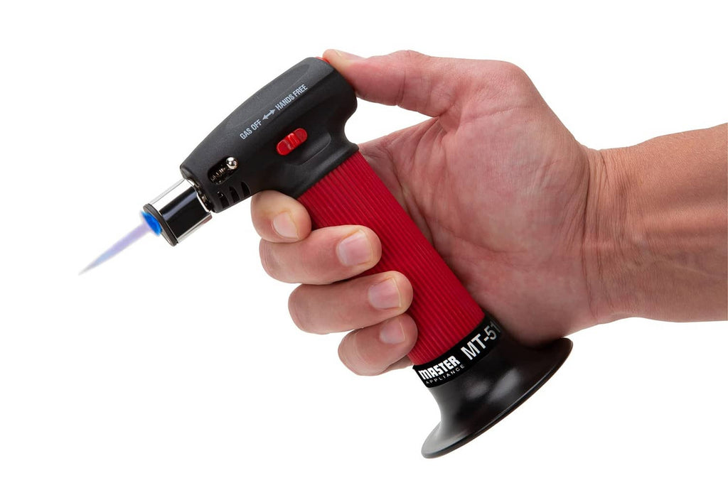 Handheld butane torch lighter with black top and red ribbed handle in use.