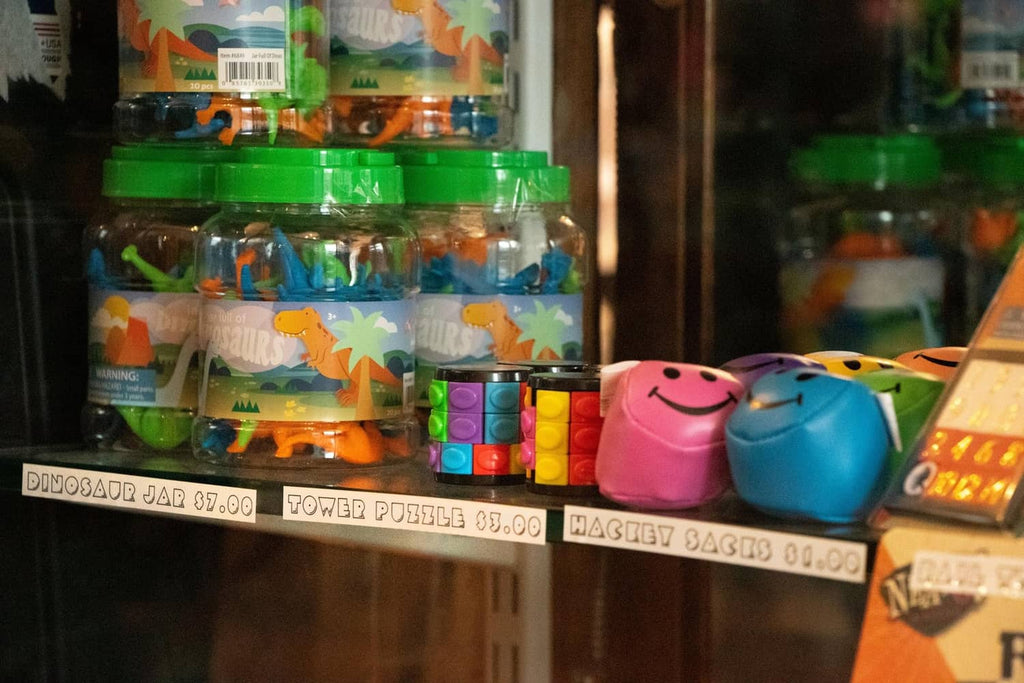Shelf display with small colorful items and dinosaur-shaped toys in jars