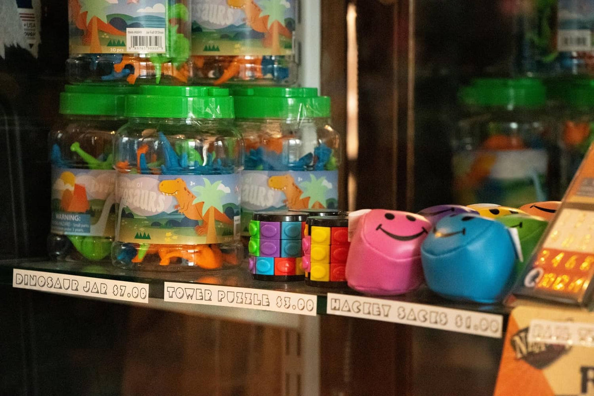 Shelf display with small colorful items and dinosaur-shaped toys in jars