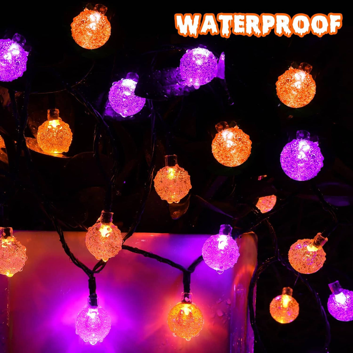 Halloween solar string lights with orange and purple glowing globe bulbs on a dark string.