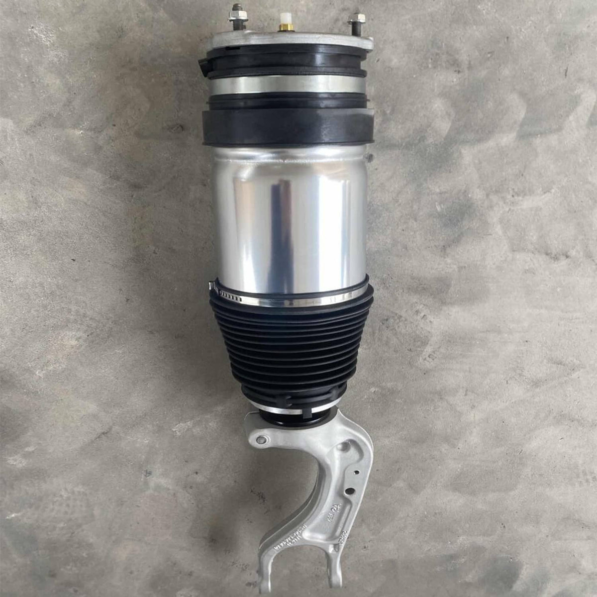 Front air suspension shock strut, silver-and-black cylinder with mounting fork bracket.