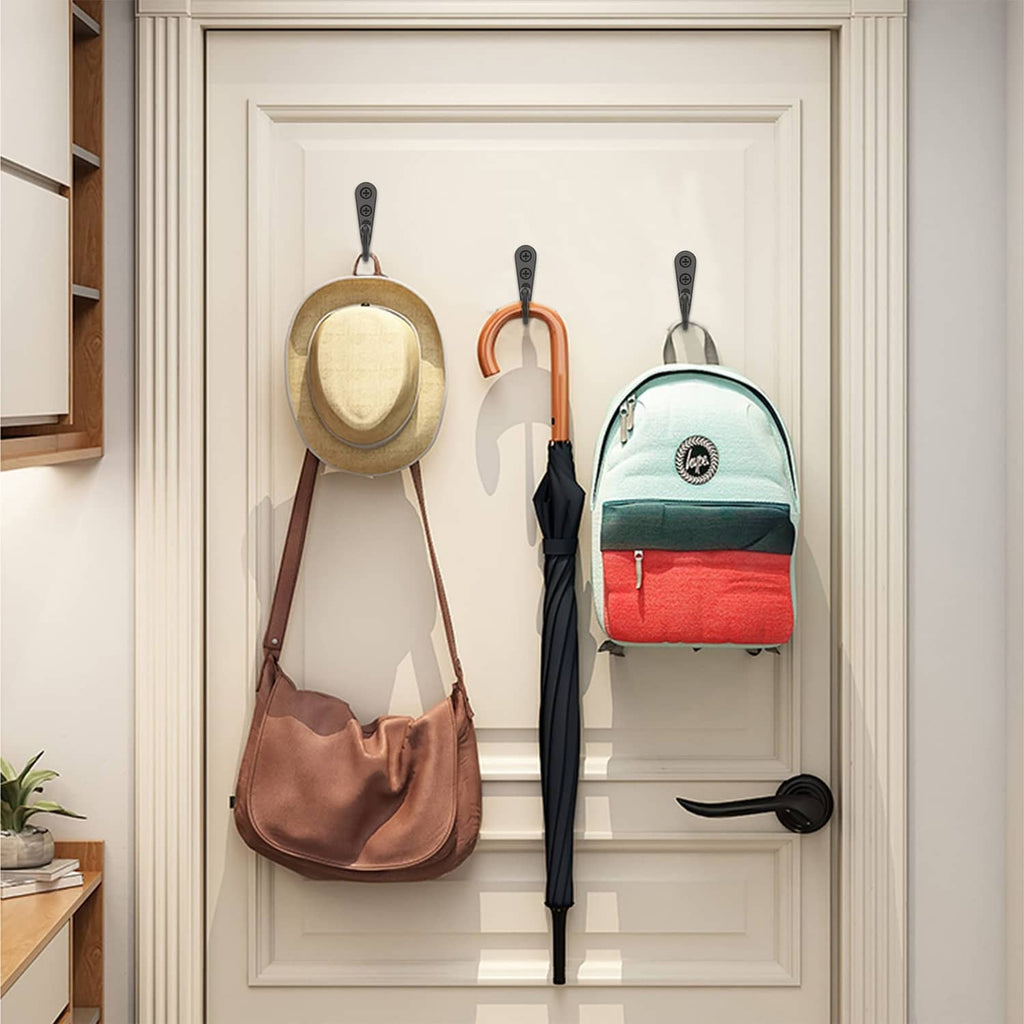 Black wall coat hooks on a rail holding bags, umbrellas, and coats