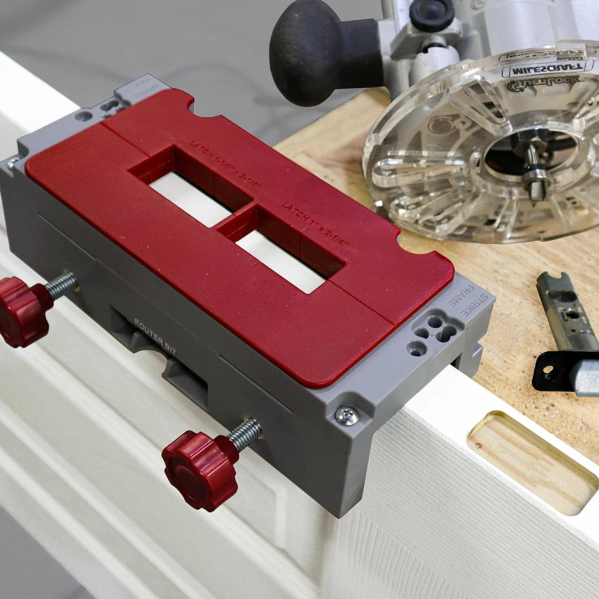Door hinge mortising jig with red template plate and clear router bit over door frame