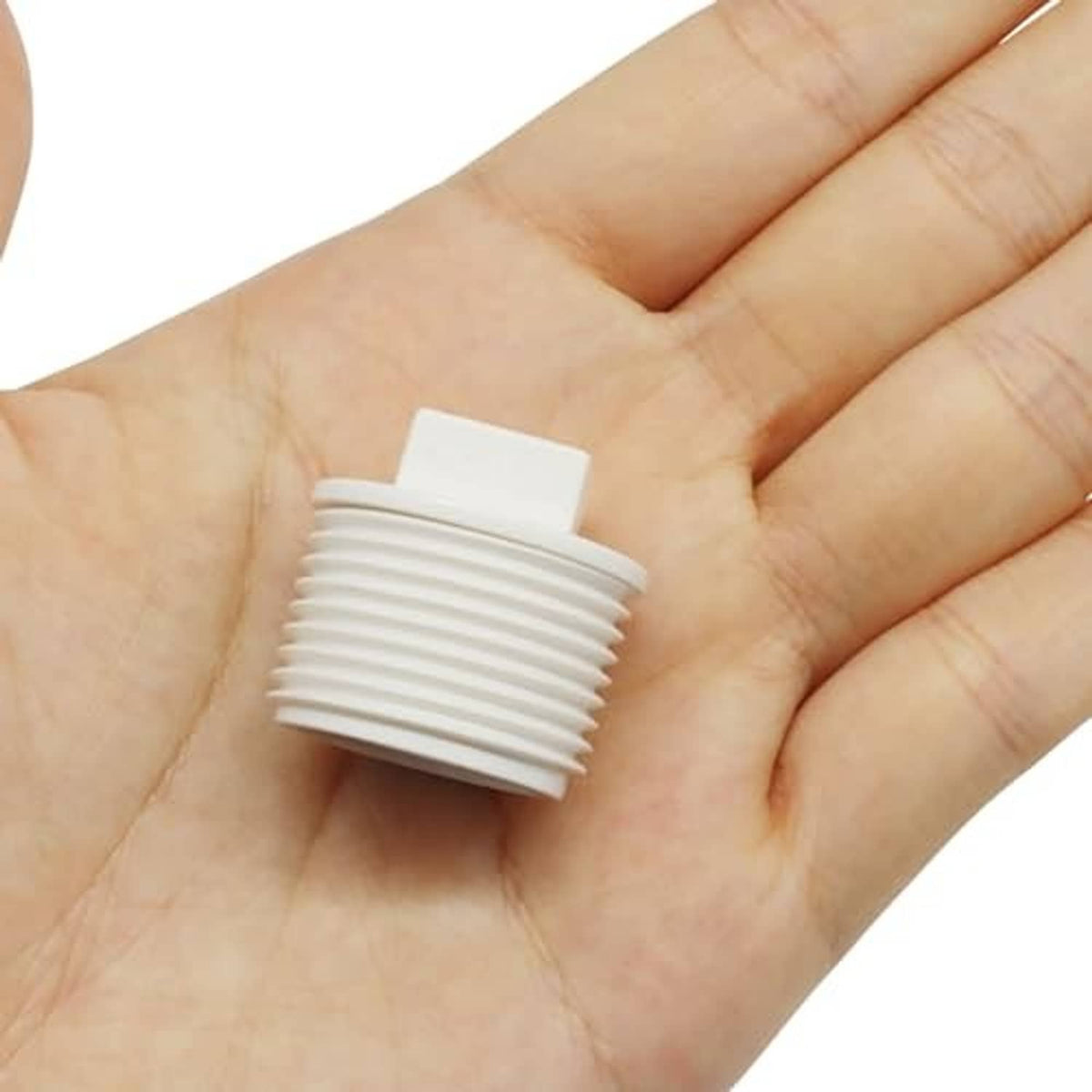 White PVC male-thread pipe end cap plug held in palm, 3/4 in size