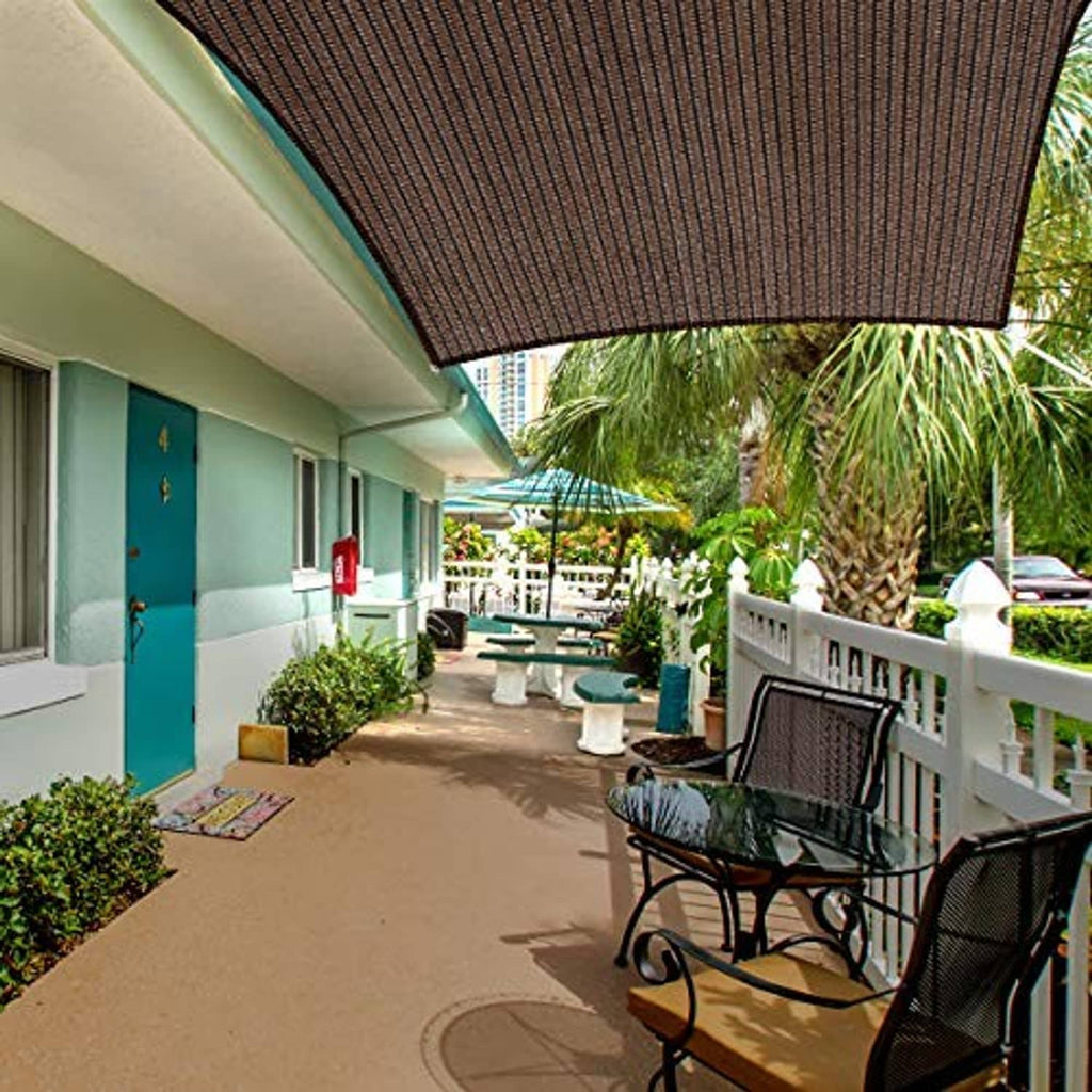Brown rectangular shade sail installed under a building overhang above a patio walkway