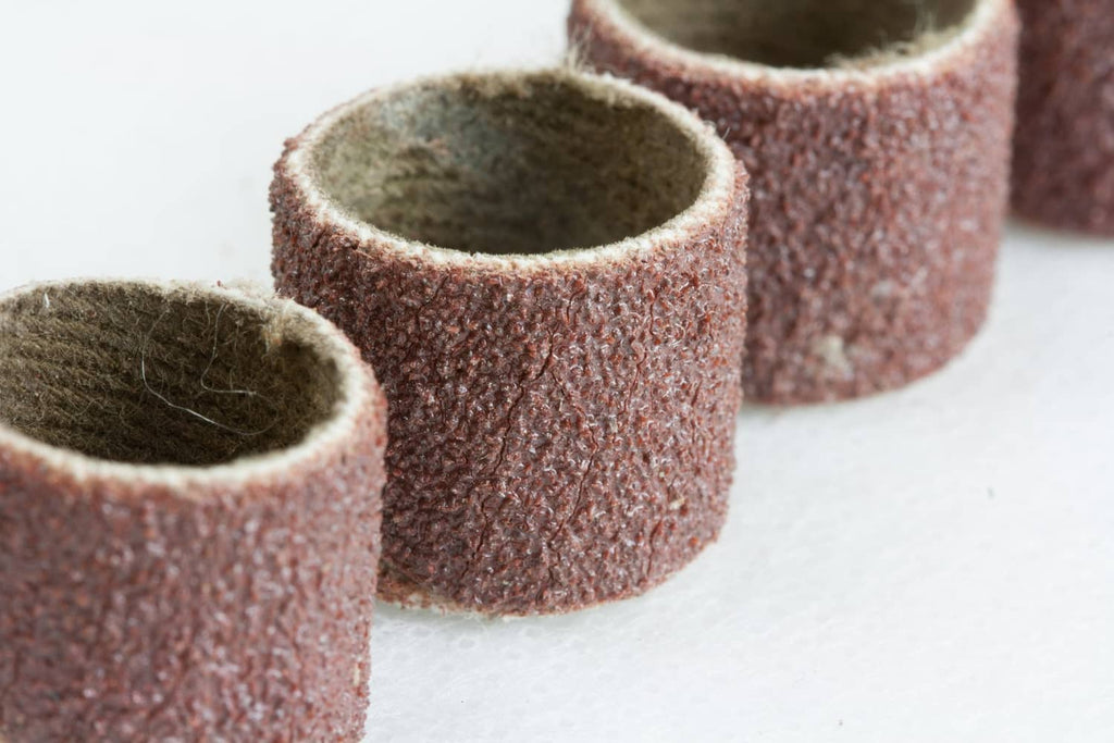 Rotary tool abrasive sanding sleeves with brown/purple grit on holders