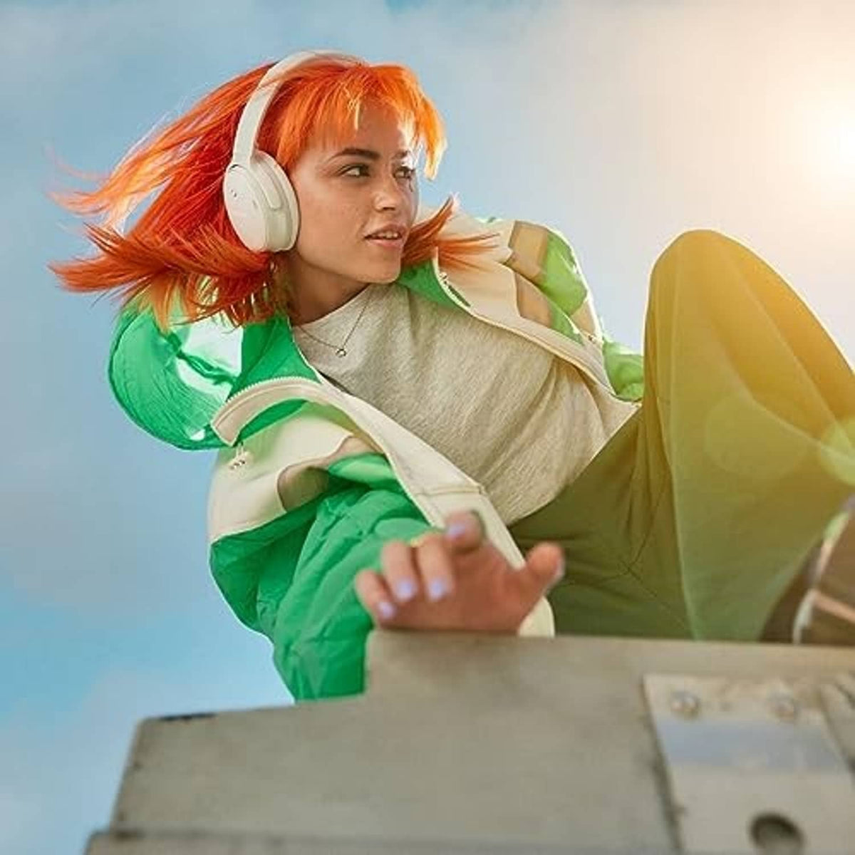 White wireless headphones worn by a person with orange hair