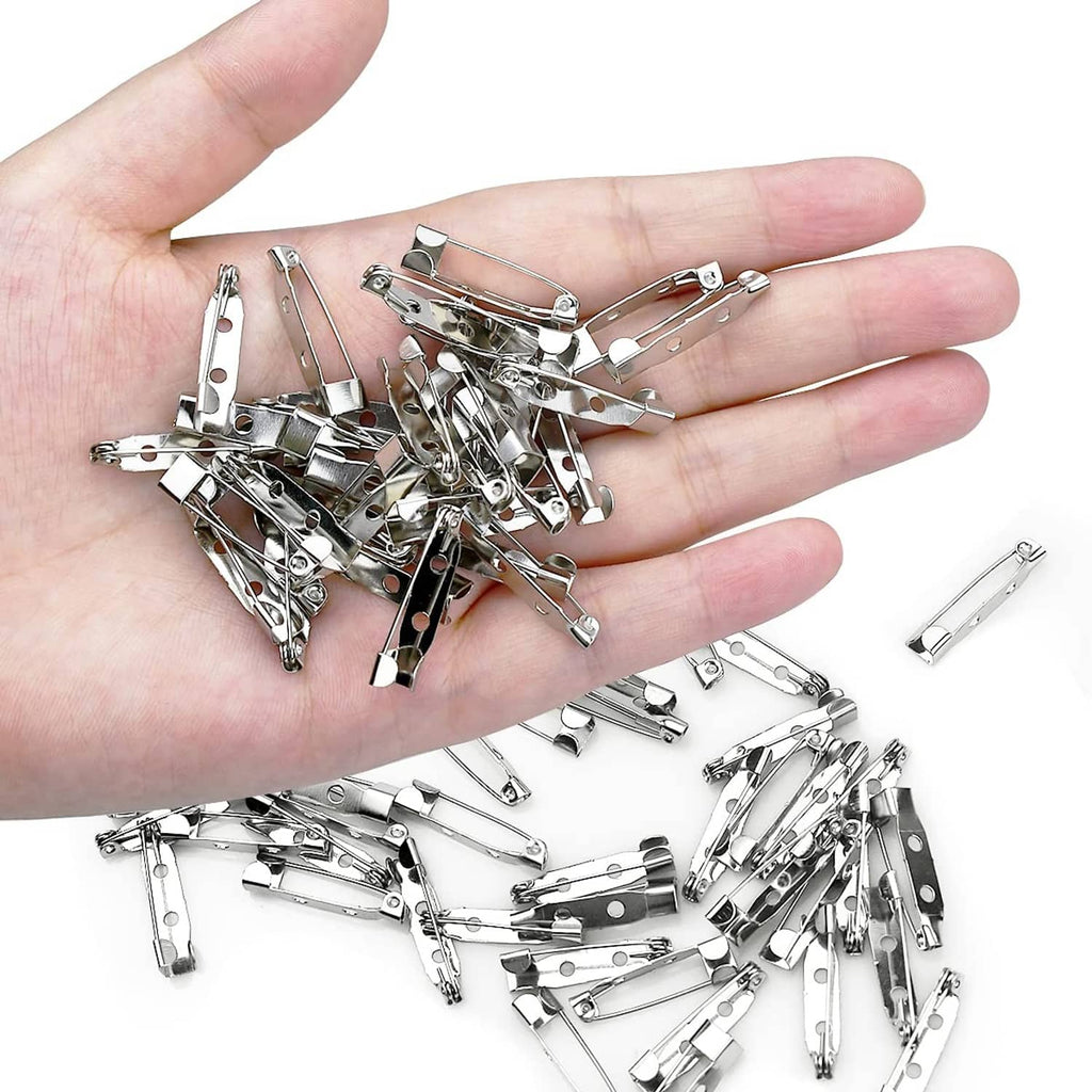 Silver bar pin brooch clasps scattered in open palm, showing safety hinge and prongs