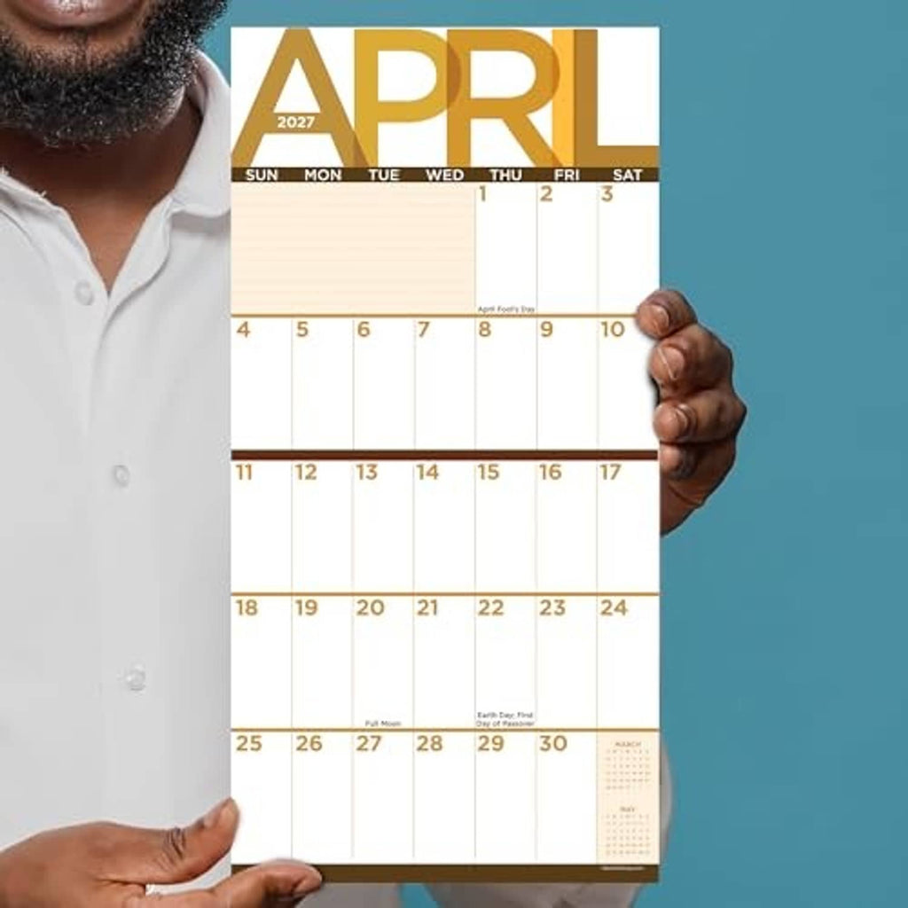 April 2027 monthly calendar sheet held in hands, showing Sunday to Saturday grid