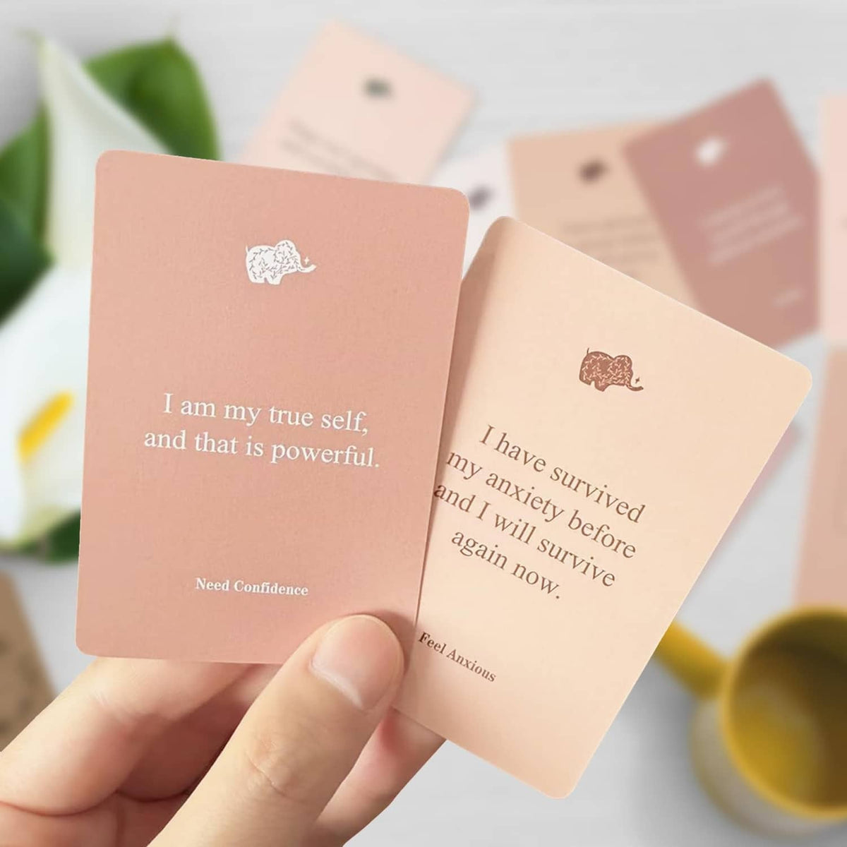 Two pink affirmation cards held up: “I am my true self” and “I have survived”