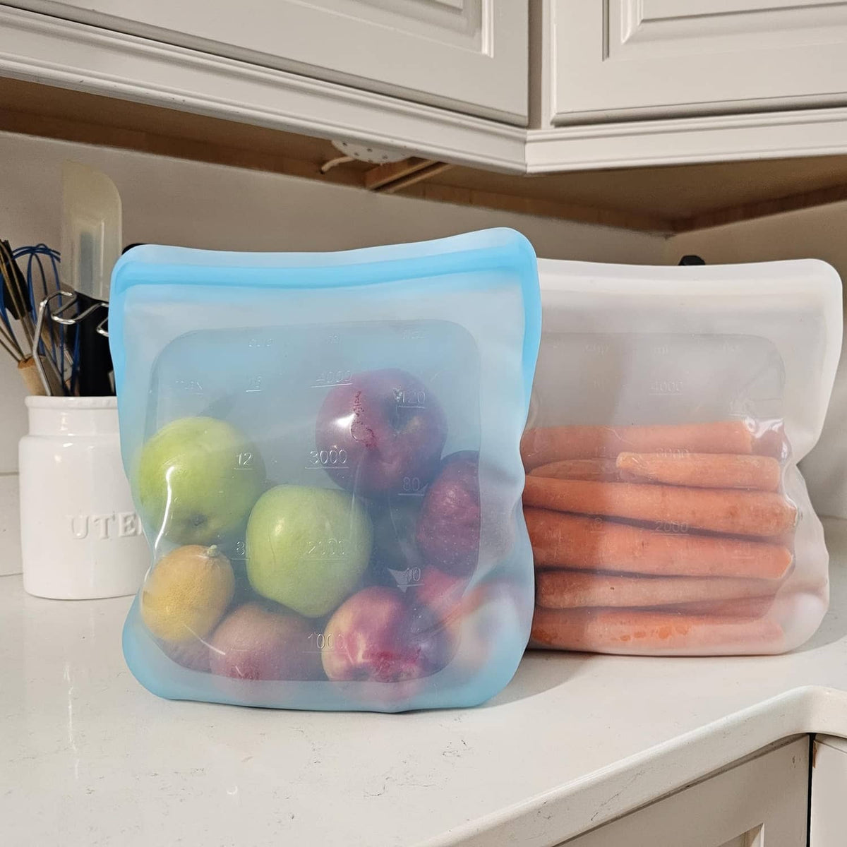 Silicone storage bags: blue pouch with fruit and white pouch with carrot sticks