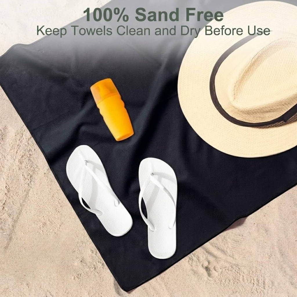Black microfiber towel laid flat on sand for travel or beach use