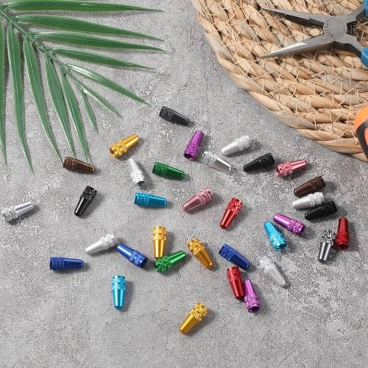 Scattered aluminum Presta valve caps in mixed colors on a light concrete surface