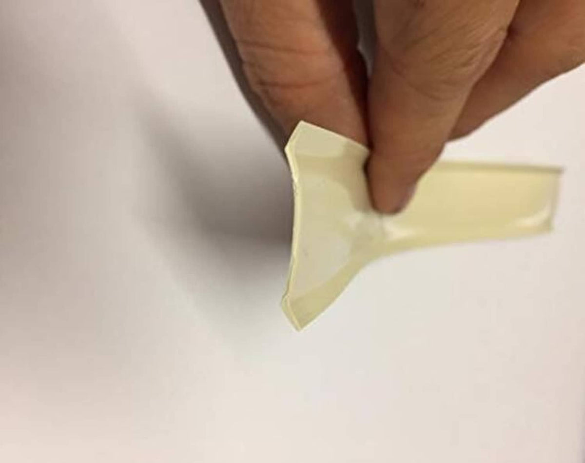 Light tan vinyl trim being pressed by hand onto a smooth surface