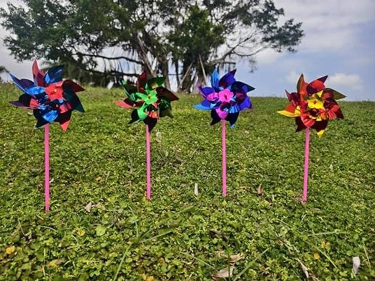 Set of multicolor plastic pinwheels on pink sticks planted in grass