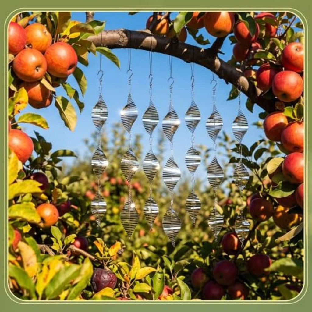 Silver stainless steel wind spinner bird deterrents hanging among fruit tree branches
