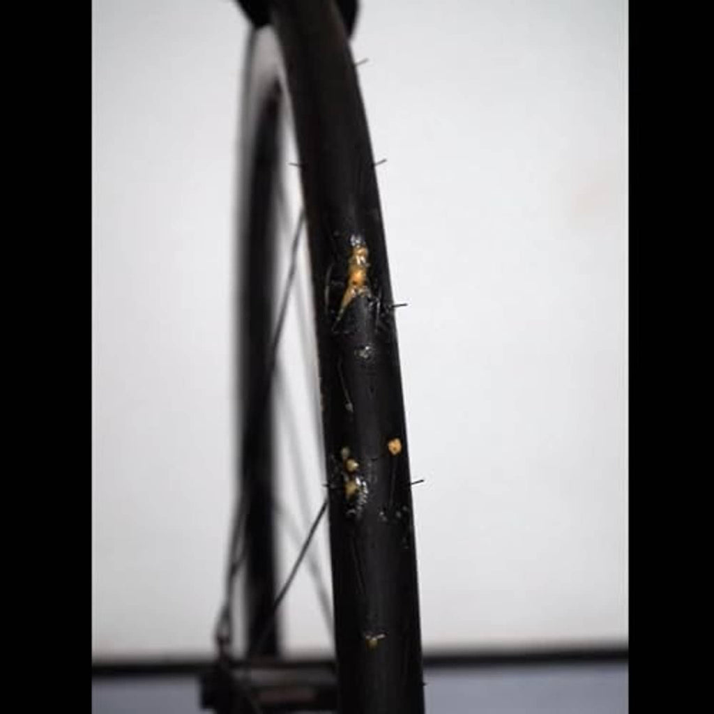Black bicycle tire with visible puncture/damage on sidewall near rim