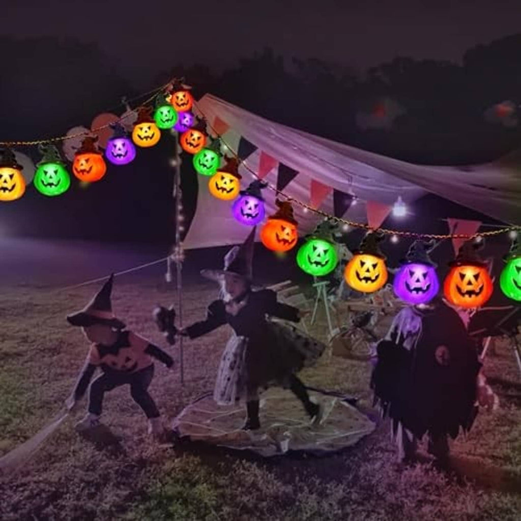 Solar pumpkin string lights with multicolor glowing jack-o'-lantern bulbs on a yard Halloween scene.
