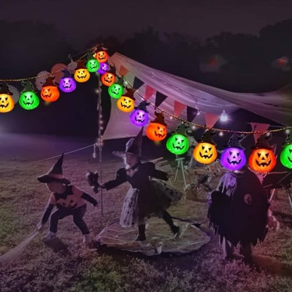 Solar pumpkin string lights with multicolor glowing jack-o'-lantern bulbs on a yard Halloween scene.