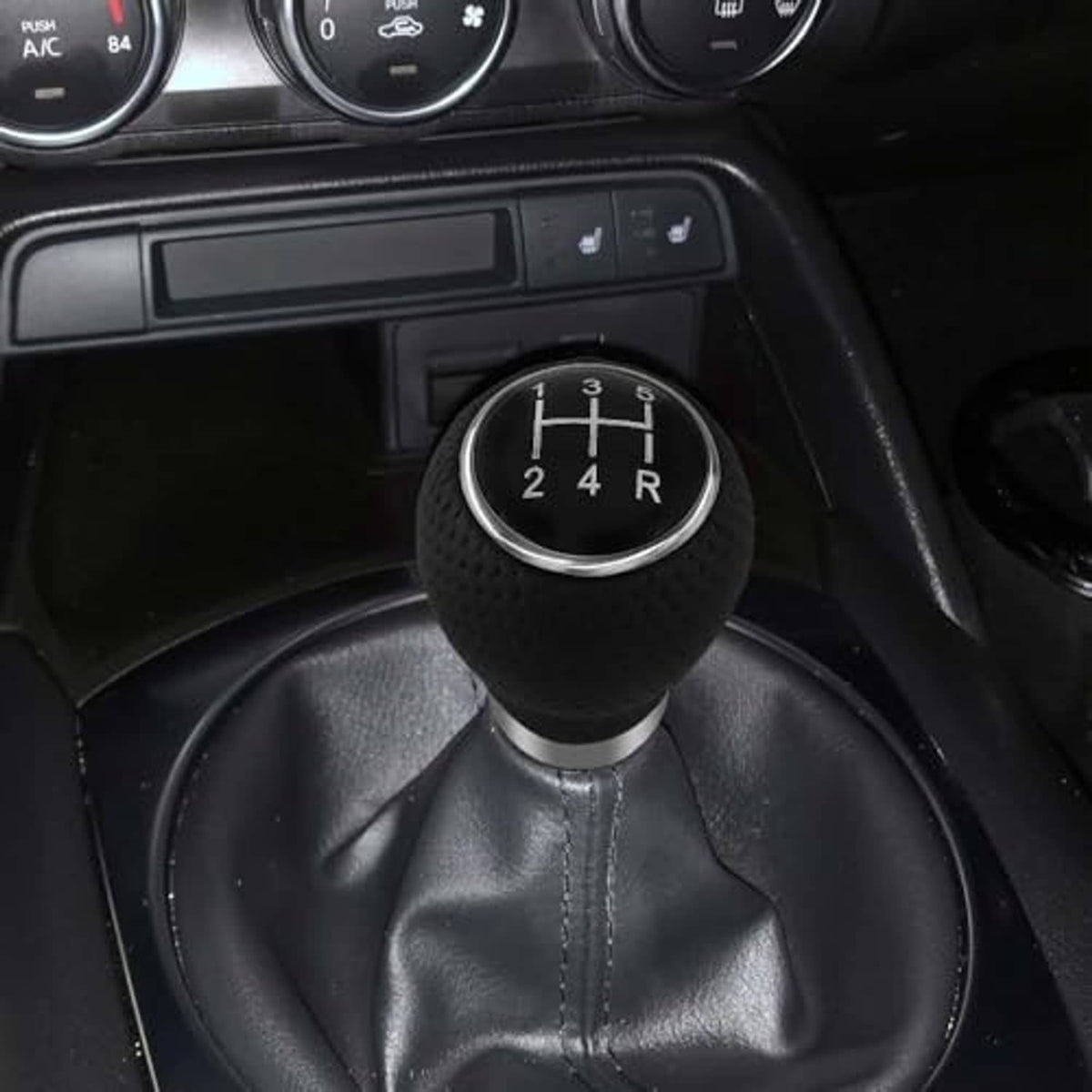 Black gear shift knob with silver ring on leather shift boot