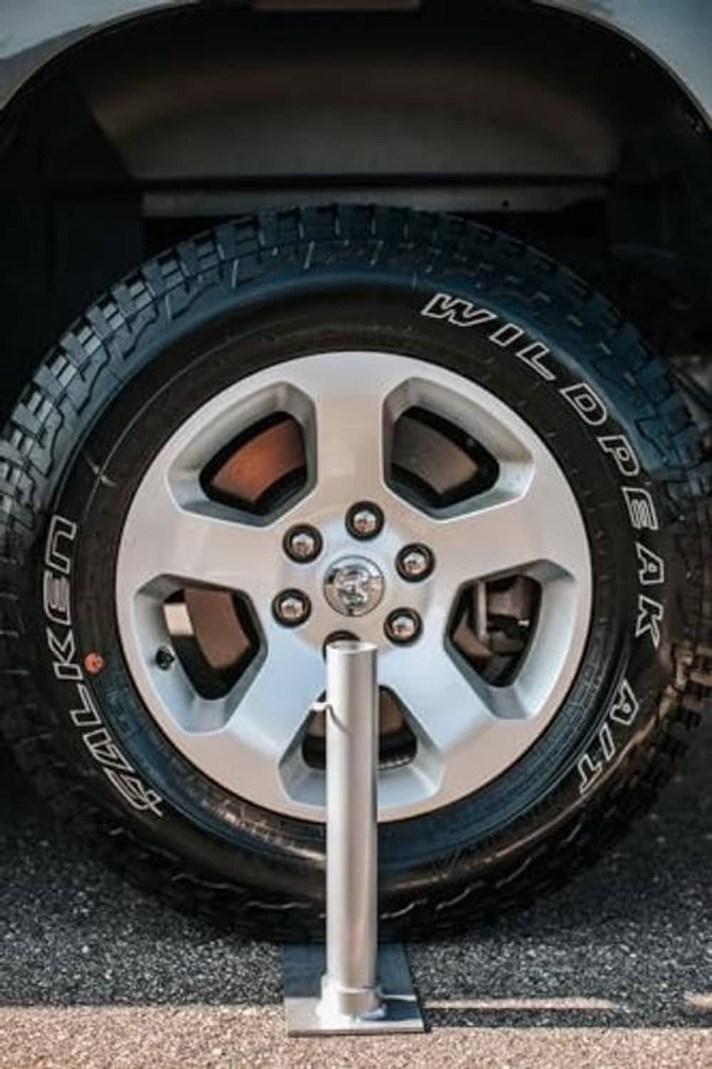 Close-up: silver upright flagpole post mounted in tire area with base plate