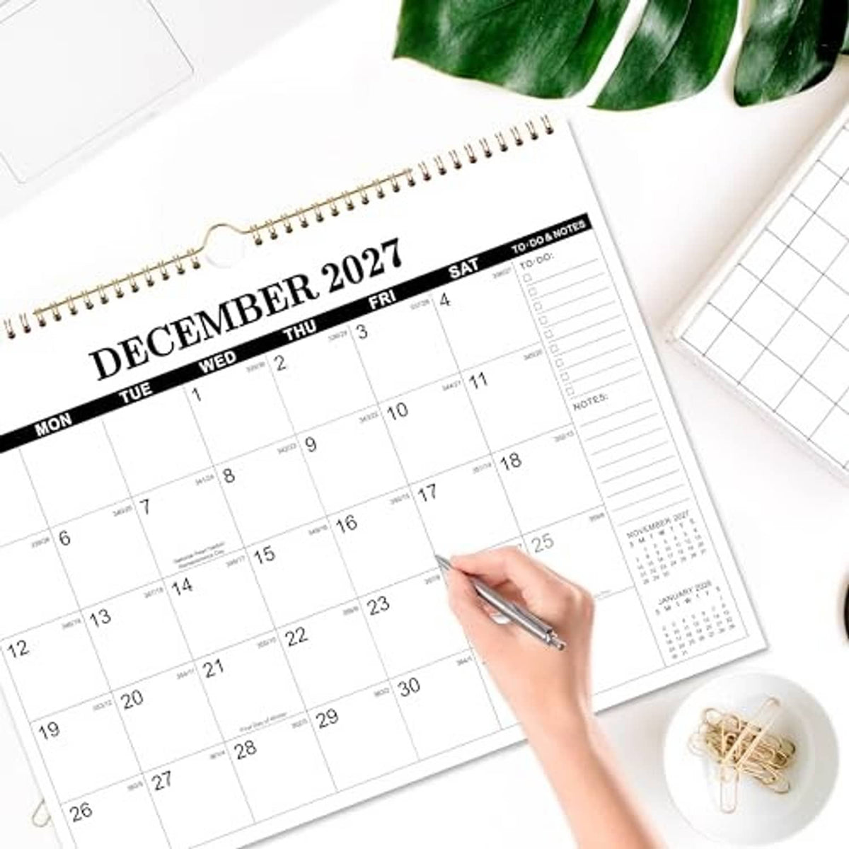 December 2027 wall calendar with hand marking the date grid and to-do & notes