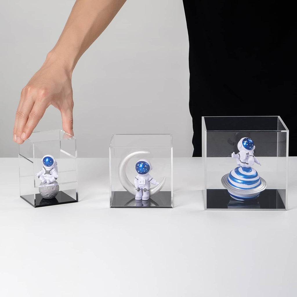 Clear acrylic display boxes with open fronts; hand placing a collectible
