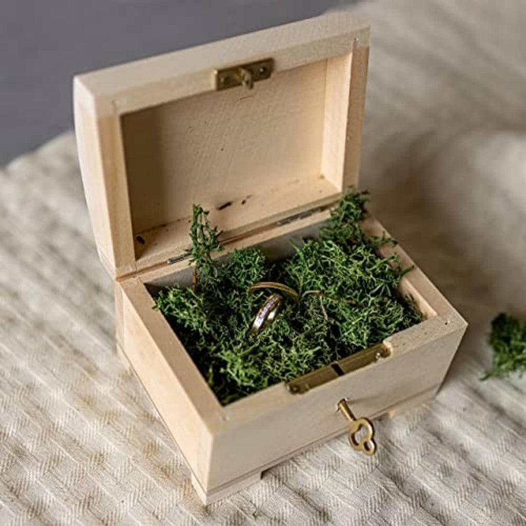 Wooden jewelry box open with green filler and ring resting in the compartment