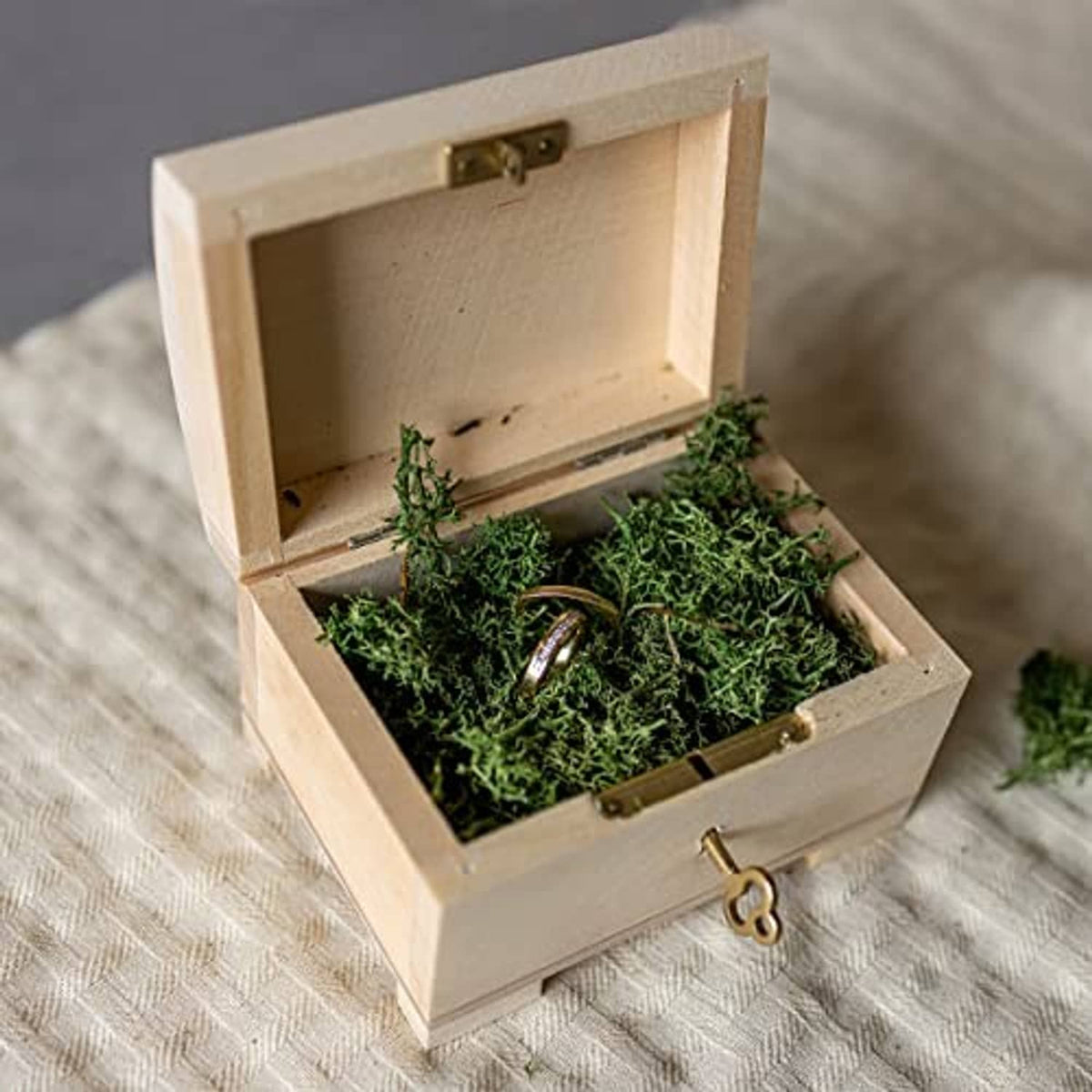 Wooden jewelry box open with green filler and ring resting in the compartment