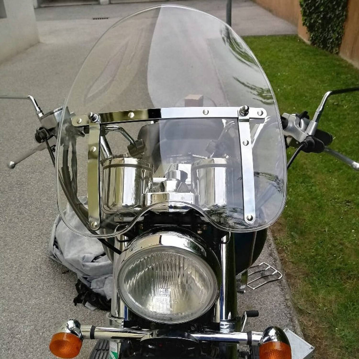 Clear motorcycle windshield with metal mounting frame and clear bracket supports.