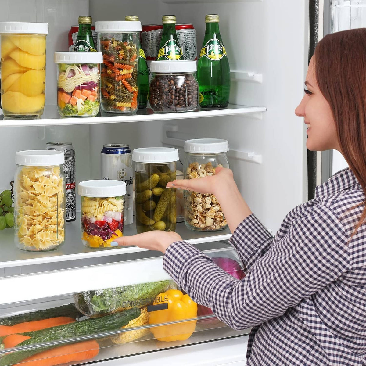 White wide-mouth mason jar lids on filled glass jars in a refrigerator