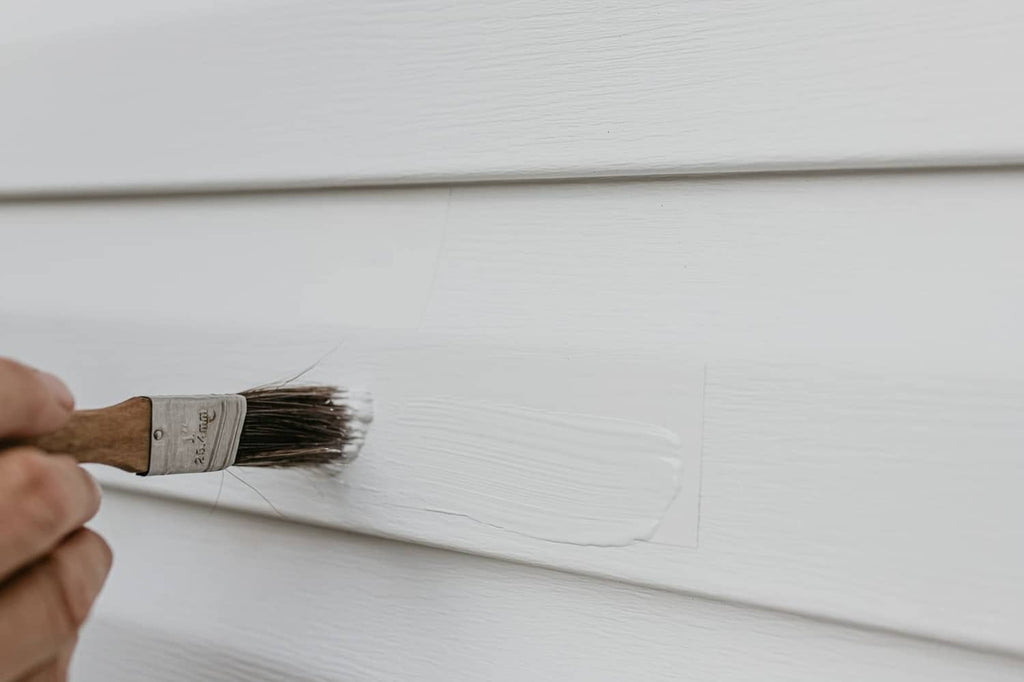 Mendyl vinyl siding repair: brush spreading repair material on white vinyl siding