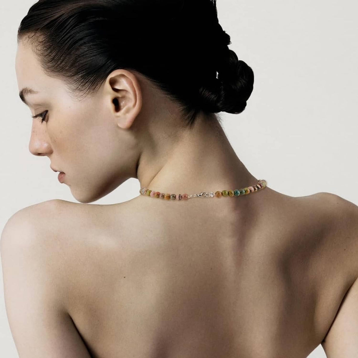 Multicolor necklace with lobster-claw clasp closure shown on model’s back
