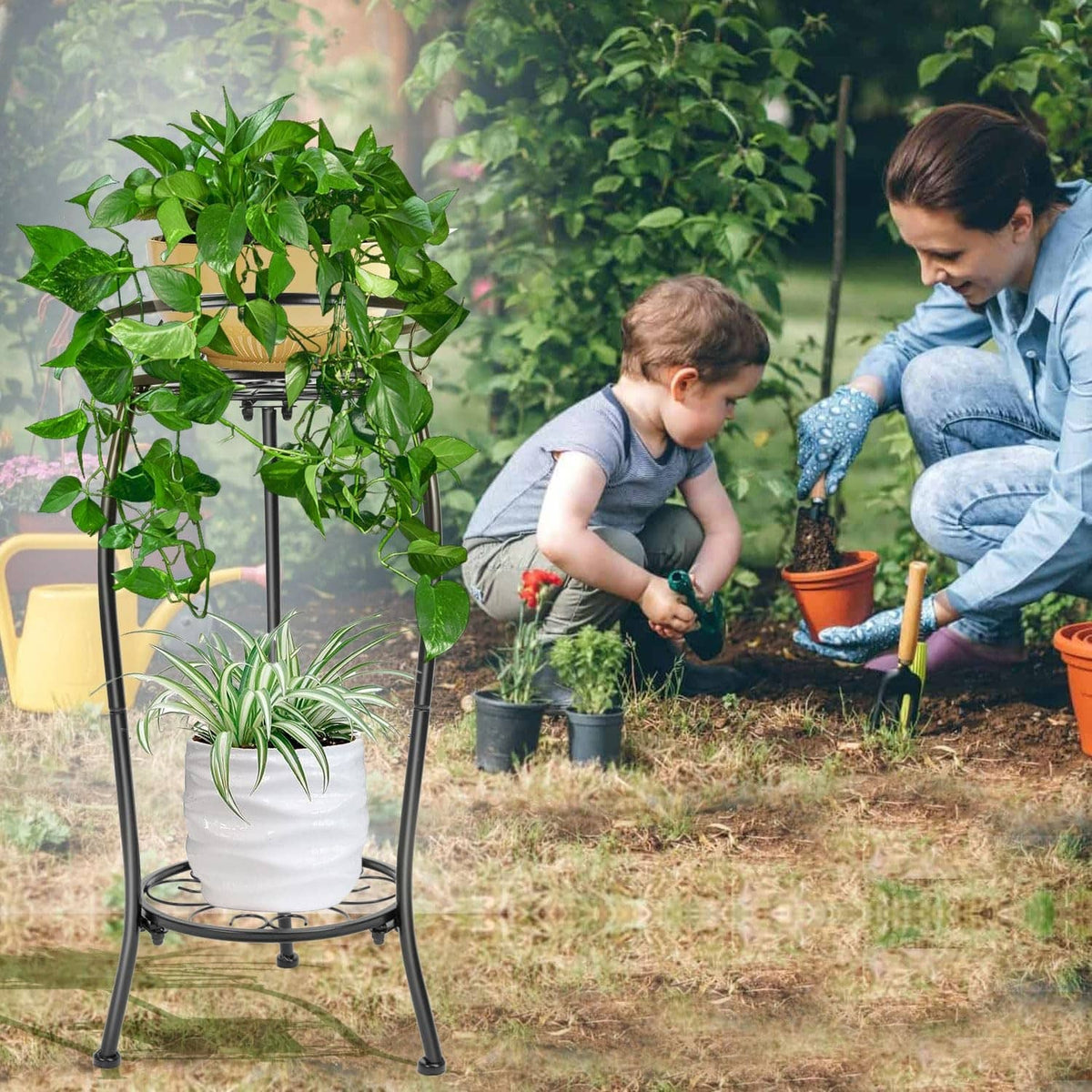 Black outdoor 2-tier metal plant stand with potted plants on two round shelves